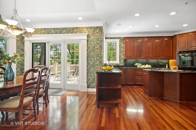 kitchen featuring dark wood-type flooring, hanging light fixtures, ornamental molding, a notable chandelier, and oven