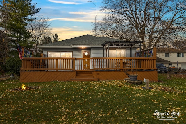 back house at dusk featuring a yard and a wooden deck