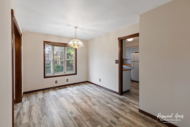 unfurnished dining area with light wood-type flooring and a notable chandelier