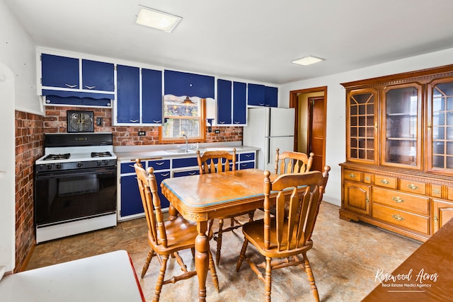 kitchen featuring brick wall, white appliances, blue cabinets, exhaust hood, and sink