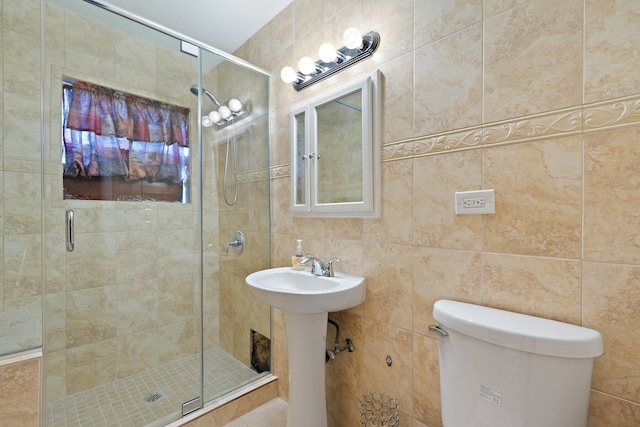 bathroom featuring toilet, tile walls, and a shower with shower door