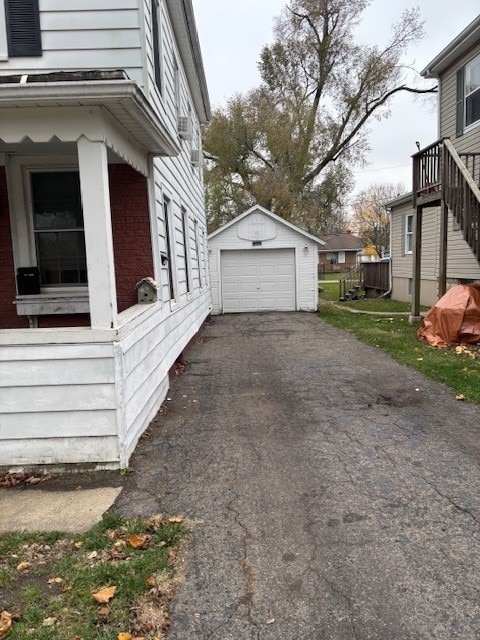 view of side of property with aphalt driveway, a detached garage, and an outdoor structure