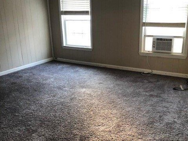 unfurnished room featuring cooling unit, baseboards, carpet, and wood walls