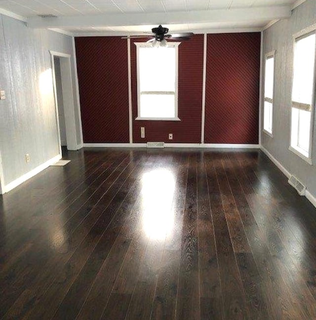 empty room featuring visible vents, baseboards, hardwood / wood-style floors, beam ceiling, and a ceiling fan