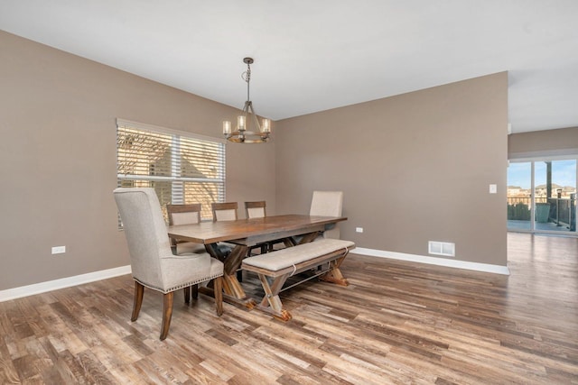 dining area featuring wood-type flooring, a healthy amount of sunlight, and a notable chandelier