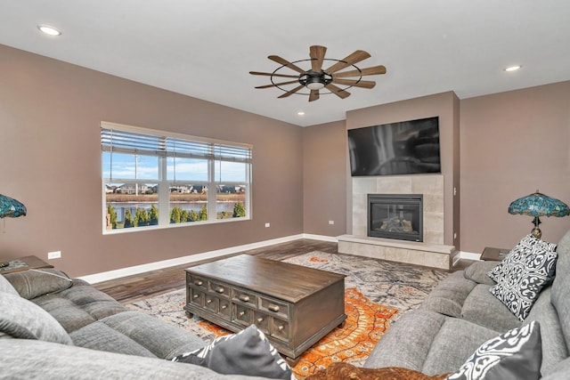 living room featuring a tile fireplace, ceiling fan, and hardwood / wood-style flooring