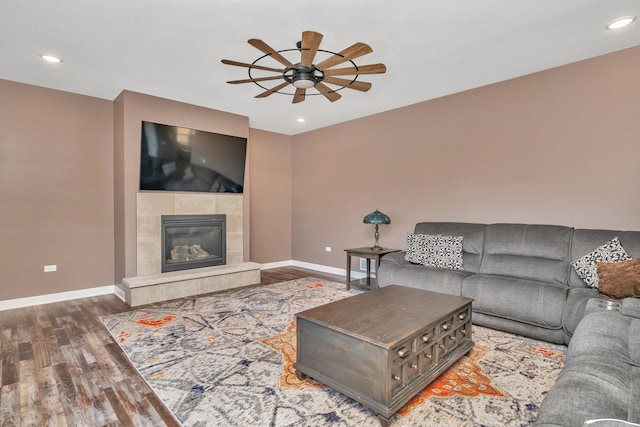 living room with hardwood / wood-style floors, ceiling fan, and a tiled fireplace