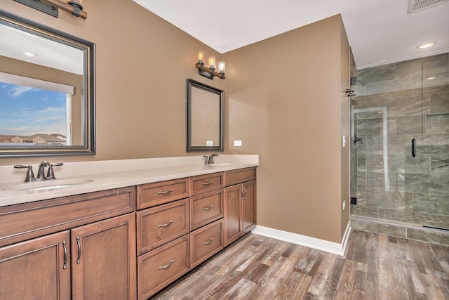 bathroom with hardwood / wood-style floors, vanity, and a shower with door