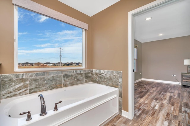 bathroom with a washtub and hardwood / wood-style flooring