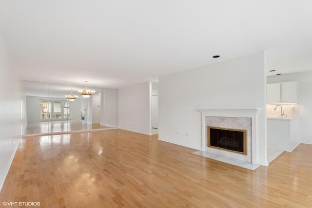 unfurnished living room featuring light hardwood / wood-style flooring, a fireplace, and a chandelier