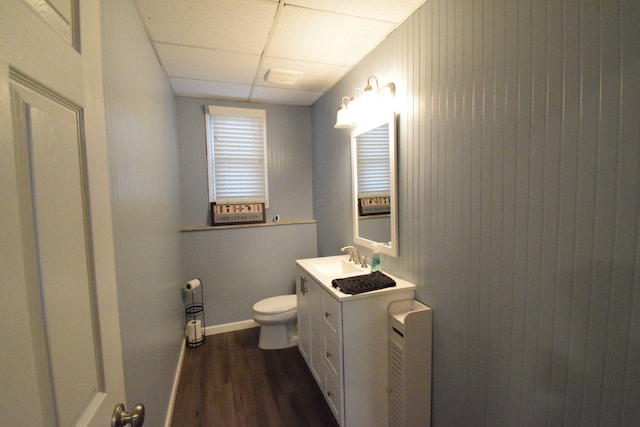 bathroom featuring wood-type flooring, vanity, toilet, and a paneled ceiling