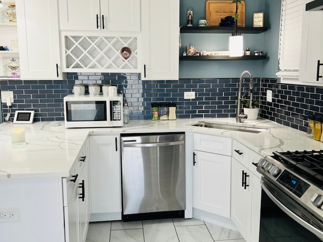 kitchen featuring white cabinets, light stone countertops, backsplash, and appliances with stainless steel finishes