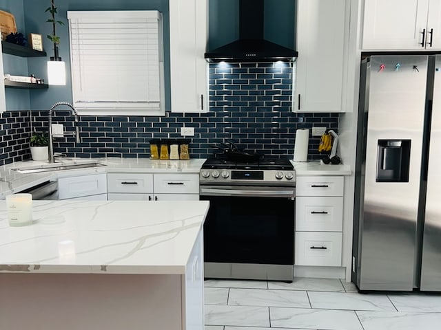 kitchen featuring backsplash, wall chimney exhaust hood, light stone counters, white cabinetry, and stainless steel appliances