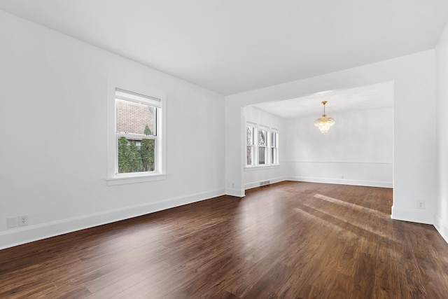 spare room featuring dark hardwood / wood-style flooring and an inviting chandelier