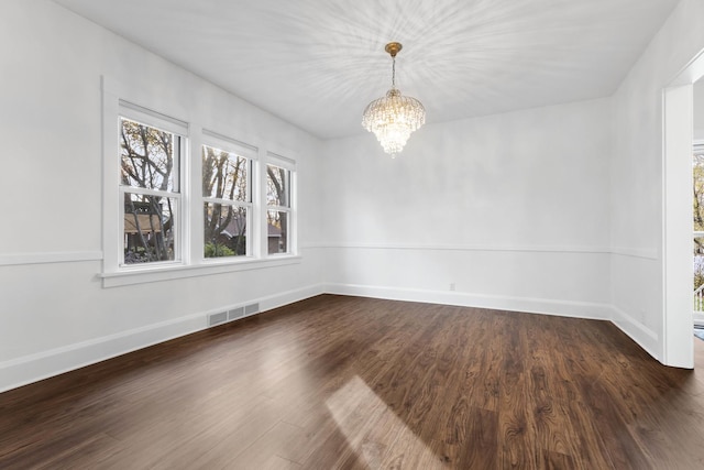 unfurnished dining area with dark hardwood / wood-style floors, a wealth of natural light, and a chandelier