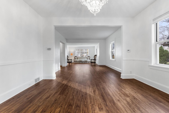 unfurnished living room featuring dark hardwood / wood-style flooring and an inviting chandelier