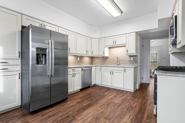 kitchen with white cabinetry, light stone counters, dark hardwood / wood-style flooring, backsplash, and appliances with stainless steel finishes