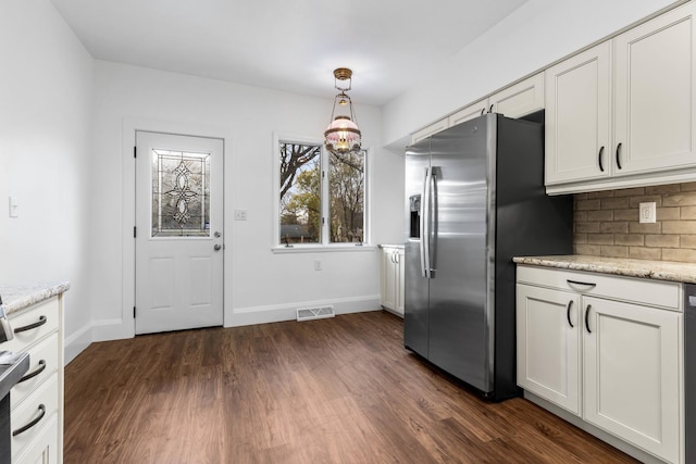 kitchen featuring white cabinetry, hanging light fixtures, light stone counters, backsplash, and stainless steel fridge