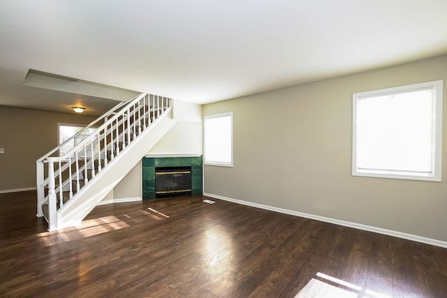 unfurnished living room with a tile fireplace and dark wood-type flooring