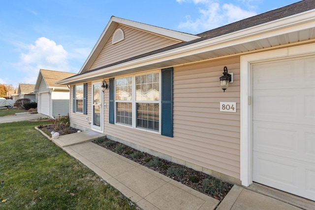 property entrance with a garage and a lawn