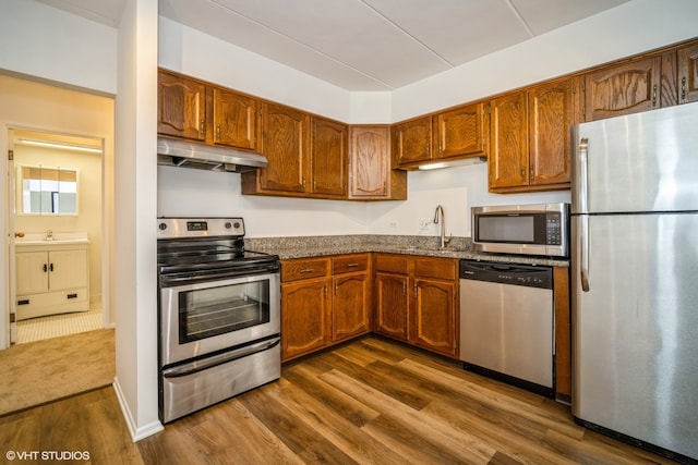 kitchen featuring stone counters, sink, dark wood-type flooring, and appliances with stainless steel finishes