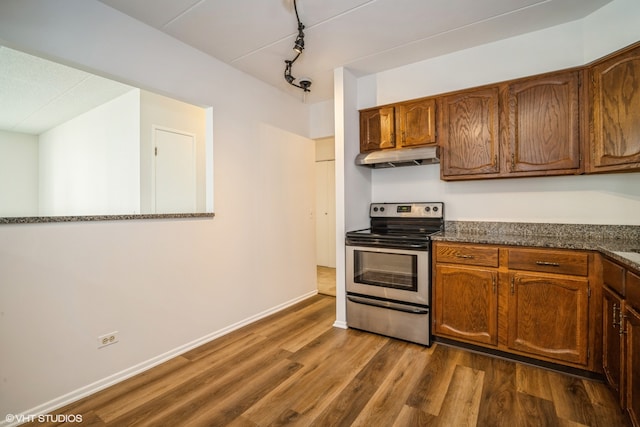 kitchen featuring dark hardwood / wood-style floors, dark stone countertops, electric stove, and rail lighting