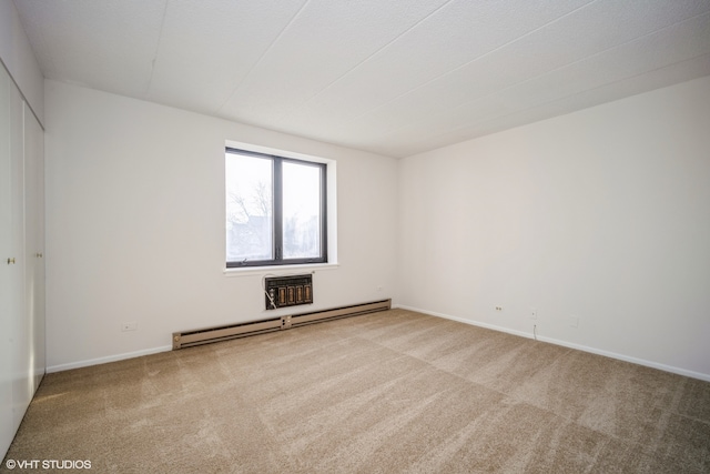 carpeted spare room with a baseboard heating unit