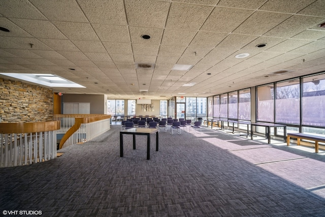 rec room featuring carpet flooring, a drop ceiling, and a wall of windows