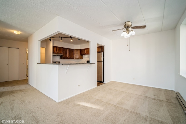 kitchen featuring ceiling fan, kitchen peninsula, light carpet, and stainless steel refrigerator