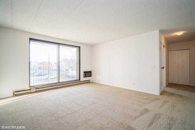 empty room featuring heating unit, light colored carpet, a baseboard radiator, and a textured ceiling