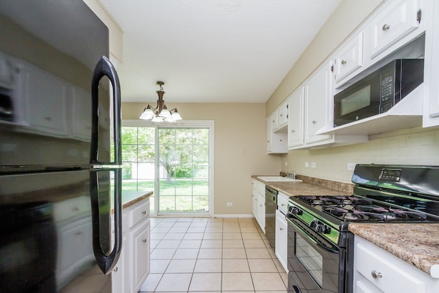 kitchen with black appliances, light tile patterned floors, decorative light fixtures, white cabinets, and a chandelier