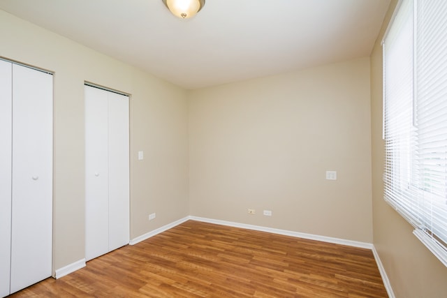 unfurnished bedroom with wood-type flooring and multiple closets