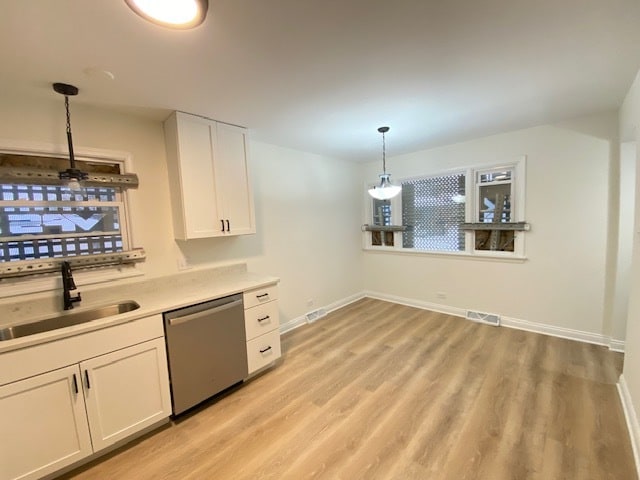 kitchen with pendant lighting, sink, stainless steel dishwasher, light hardwood / wood-style floors, and white cabinetry