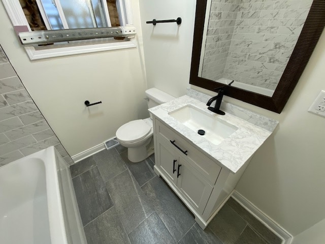 bathroom with a bathtub, vanity, and toilet