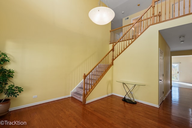 stairs featuring a towering ceiling and hardwood / wood-style flooring