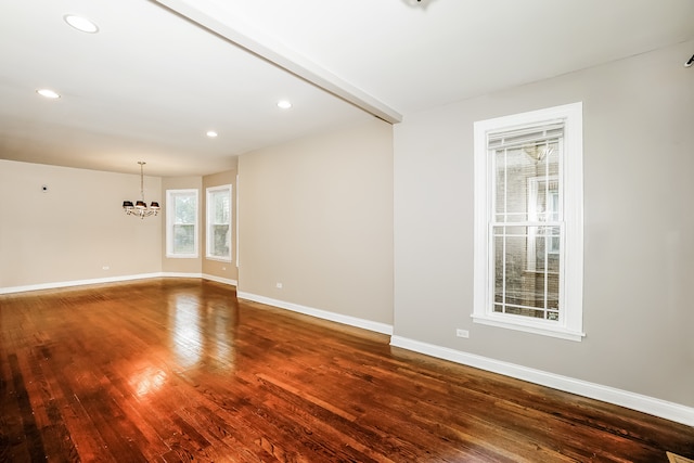 spare room featuring beamed ceiling, dark hardwood / wood-style flooring, and an inviting chandelier