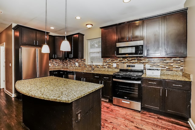 kitchen featuring dark hardwood / wood-style floors, a kitchen island, stainless steel appliances, and hanging light fixtures