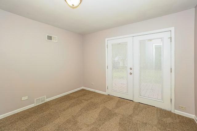 carpeted spare room featuring french doors