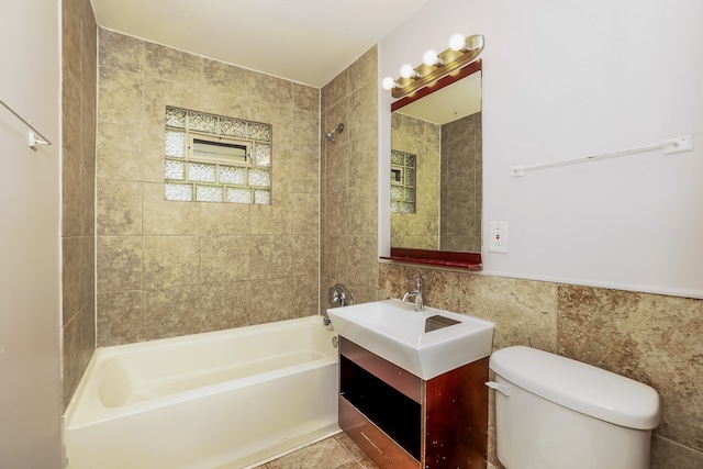 full bathroom with vanity, toilet, tile walls, and tiled shower / bath