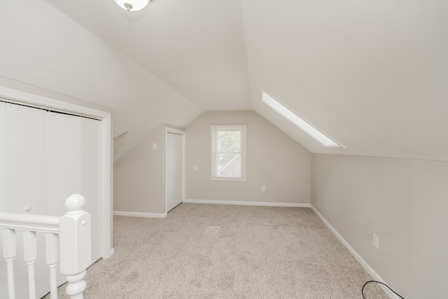 bonus room with vaulted ceiling with skylight and light carpet