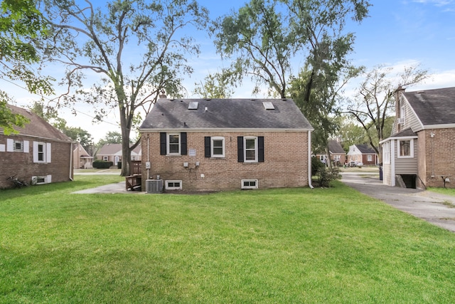 rear view of house featuring a lawn and central air condition unit