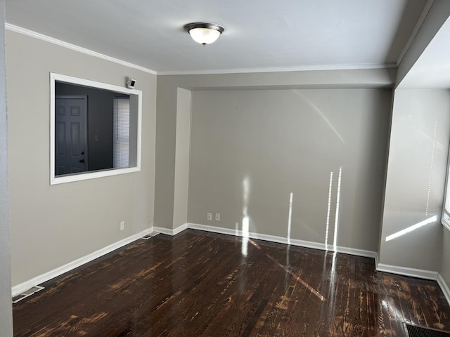 spare room with baseboards, visible vents, ornamental molding, and dark wood-type flooring