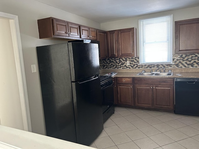 kitchen with light countertops, backsplash, a sink, dark brown cabinets, and black appliances