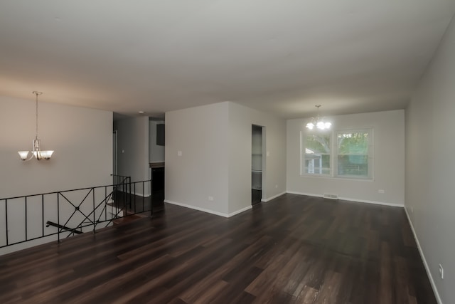 unfurnished room with a notable chandelier and dark hardwood / wood-style floors