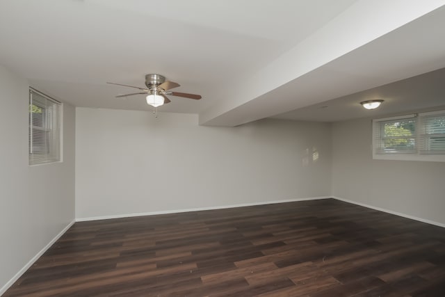 basement featuring plenty of natural light, ceiling fan, and dark hardwood / wood-style flooring