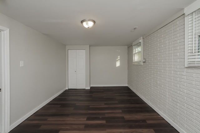 hallway with brick wall and dark hardwood / wood-style floors