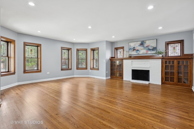 unfurnished living room with hardwood / wood-style flooring and a brick fireplace