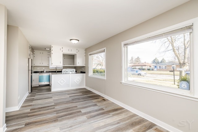 kitchen with baseboards, appliances with stainless steel finishes, light wood-style floors, and white cabinets