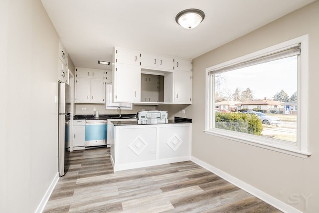 kitchen featuring baseboards, stainless steel appliances, dark countertops, and white cabinets