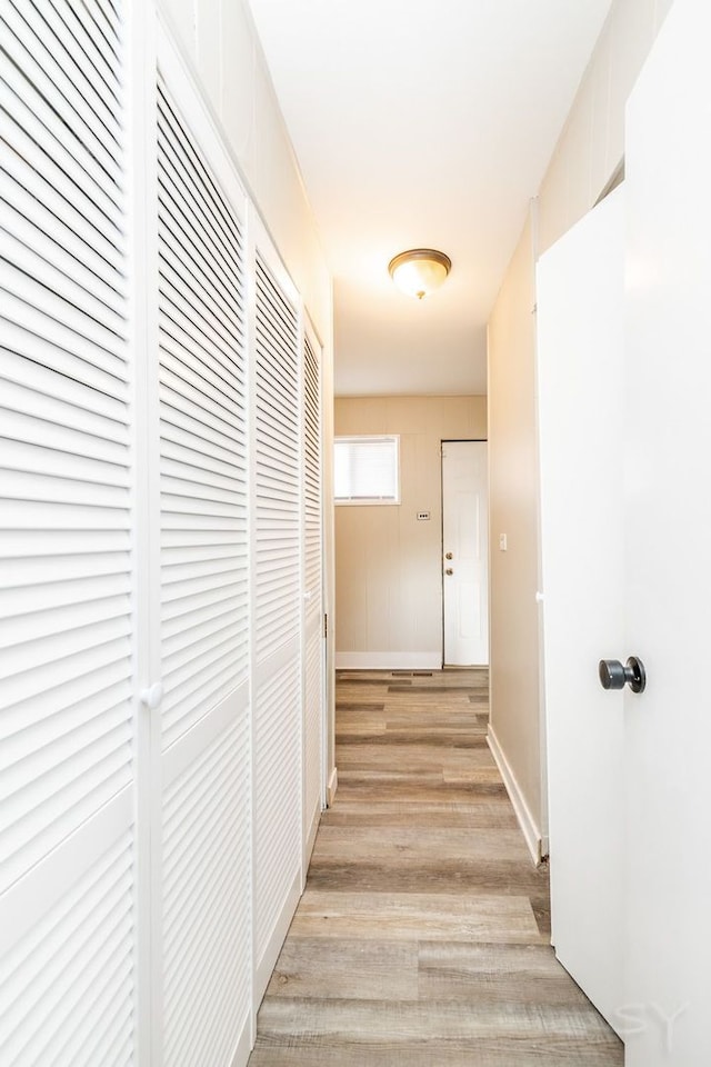 corridor with light wood-style floors and baseboards